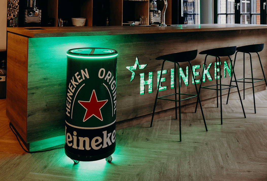 The illuminated Heineken can cooler in a bar, beside a lit Heineken wall sign